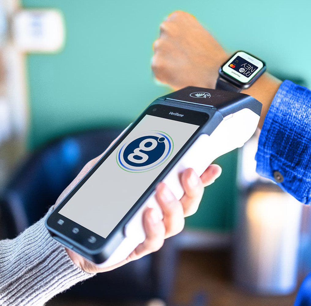 person taking a payment using a handheld terminal from someone wearing a smart watch