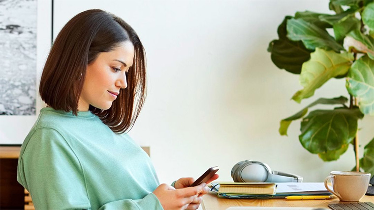 person in green jumper looking at mobile phone