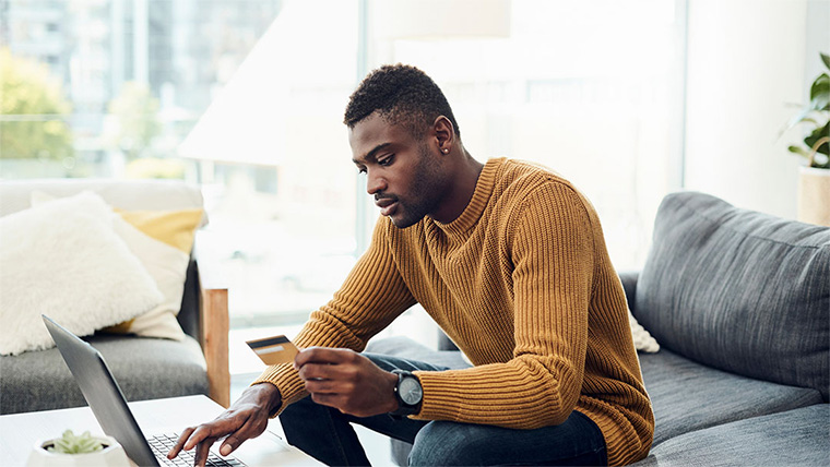 Man entering card details into a laptop.