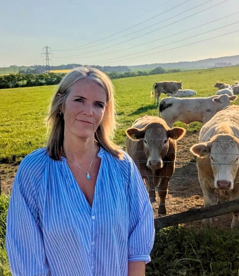 Woman standing in front of a field of cows