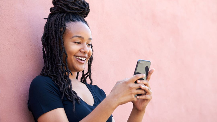 person using phone against a pink wall