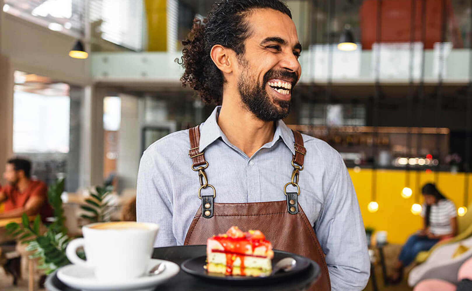 man holding tray with coffee and cake whilst smiling