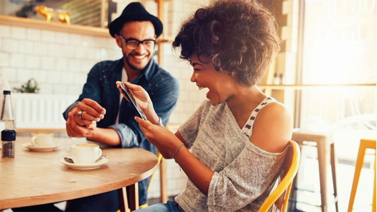 Two people having coffee looking at a mobile