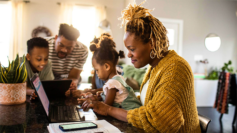 person on laptop surrounded by their two children and partner